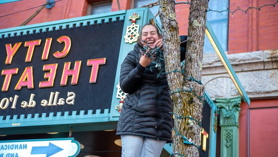 在比德福德市剧院前，一名女学生将彩灯缠在树干上