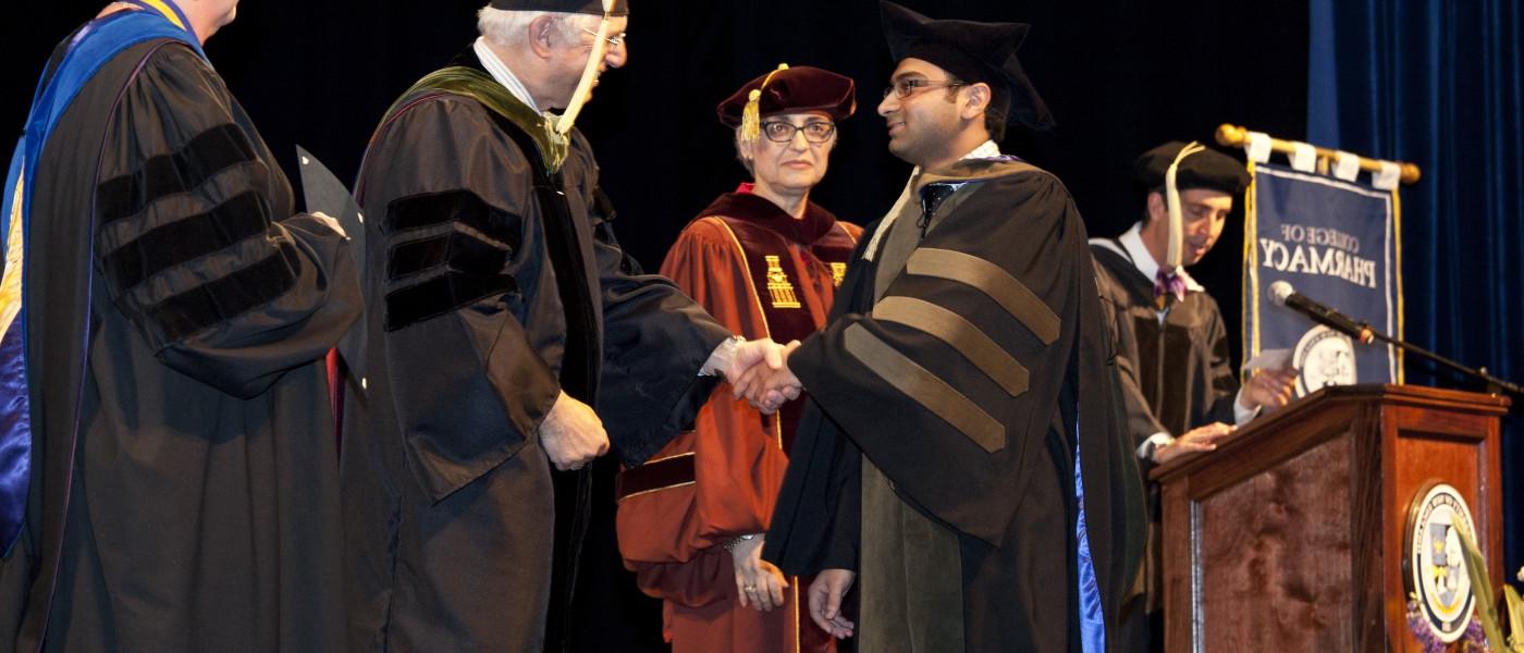 A pharmacy student accepts his diploma during commencement 