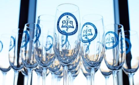Champagne flutes branded with the UNE COM logo are arranged on a table